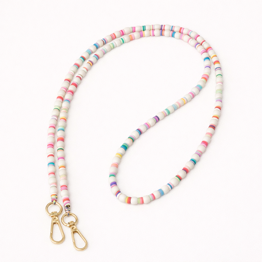 White beaded Cove LONG PHONE CHAIN with colorful striped accent beads and a gold clasp, shown as a flat lay.