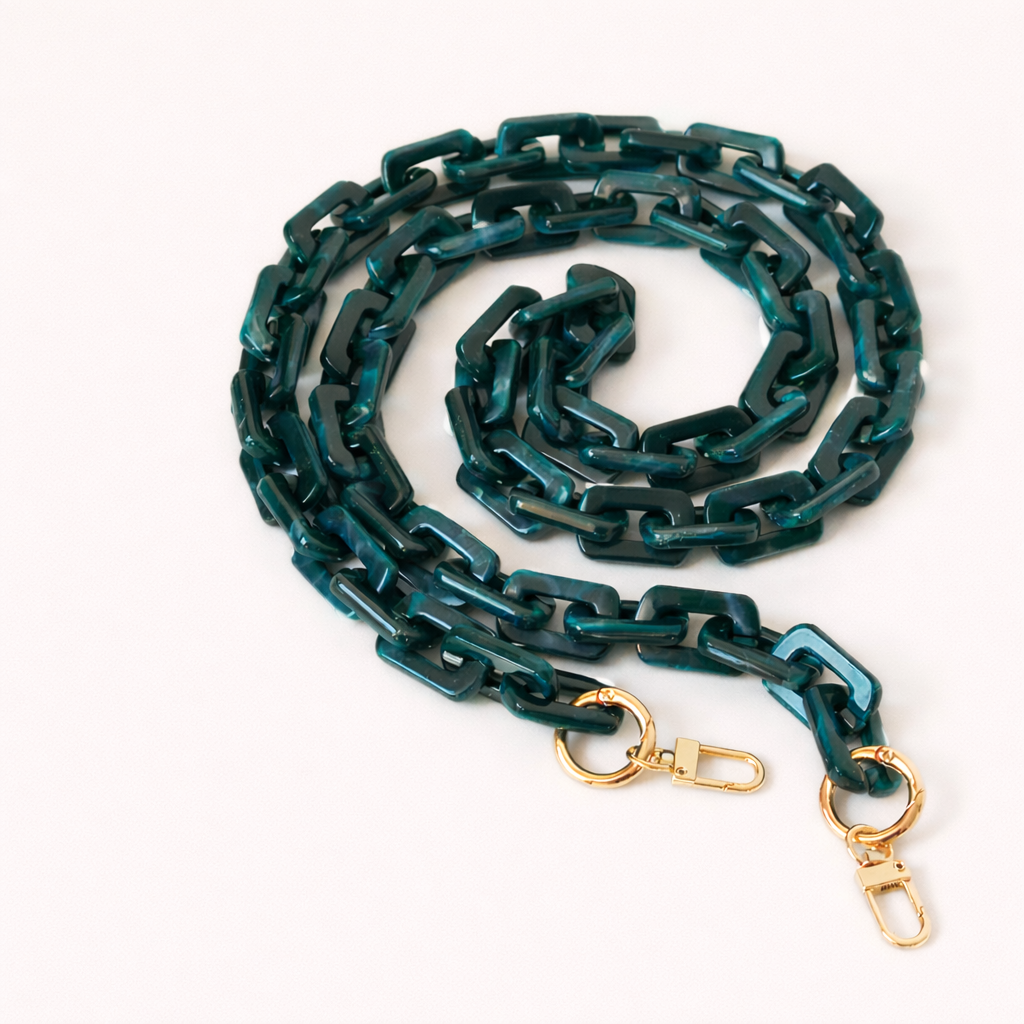 A coiled dark teal marbled acrylic paperclip-link phone chain with gold clasps, shown on a cream background.