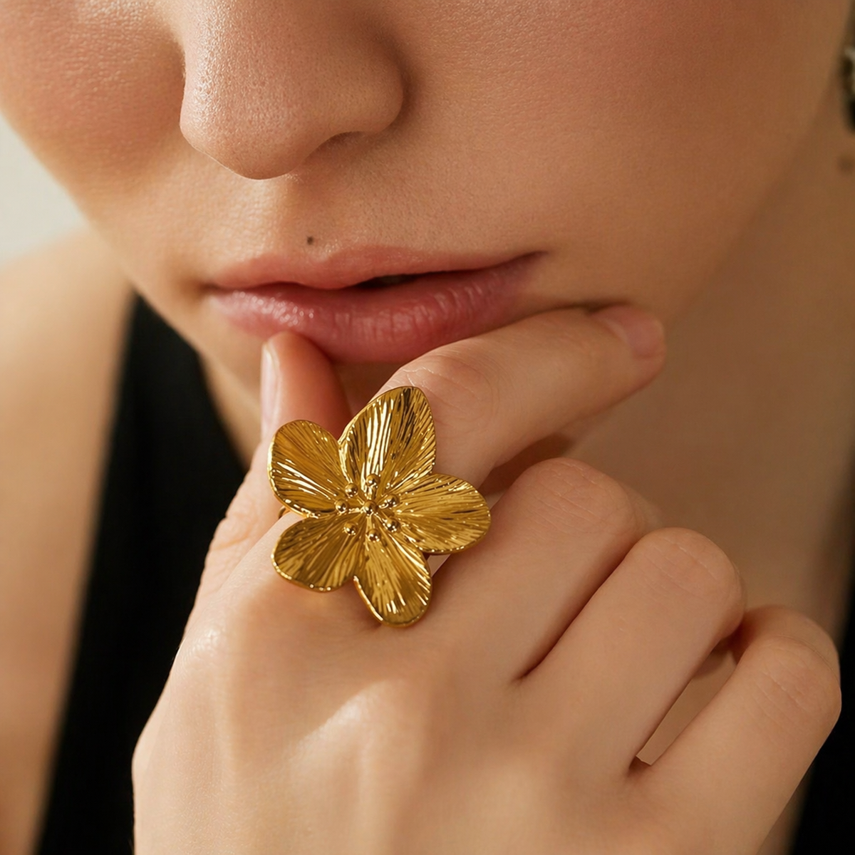 Model rests her chin on a hand wearing the gold Isle Of Paradise RING's textured flower face.