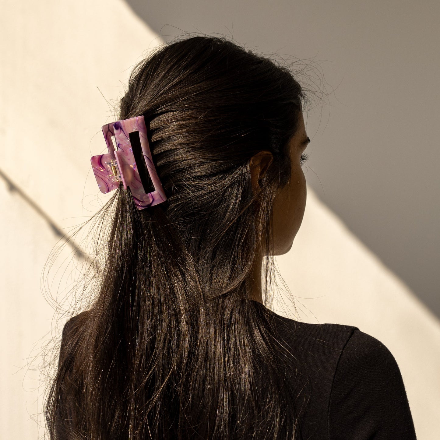 Lark HAIR CLIP in a purple marbled pattern, worn half-up on dark hair, back view in sunlight.