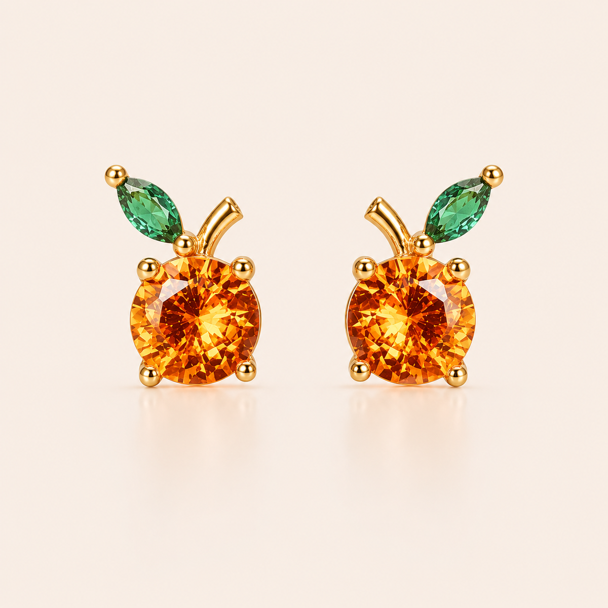 Gold stud earrings from the Little Fruit EARRINGS with a round orange cubic zirconia and a green marquise leaf, evoking a citrus fruit.