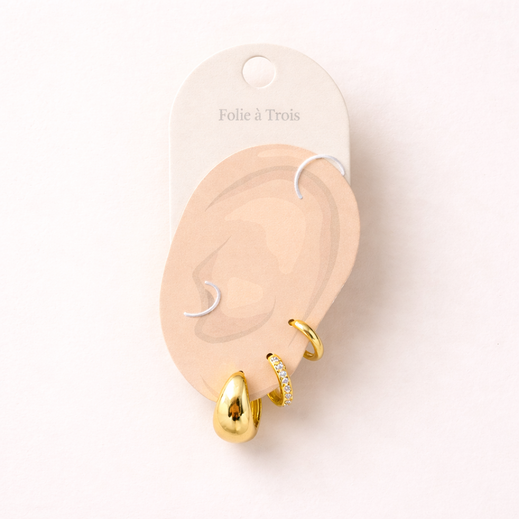 Illustrated Folie a Trois earring card showing the gold Lulu Set pieces on an ear-shaped display card.