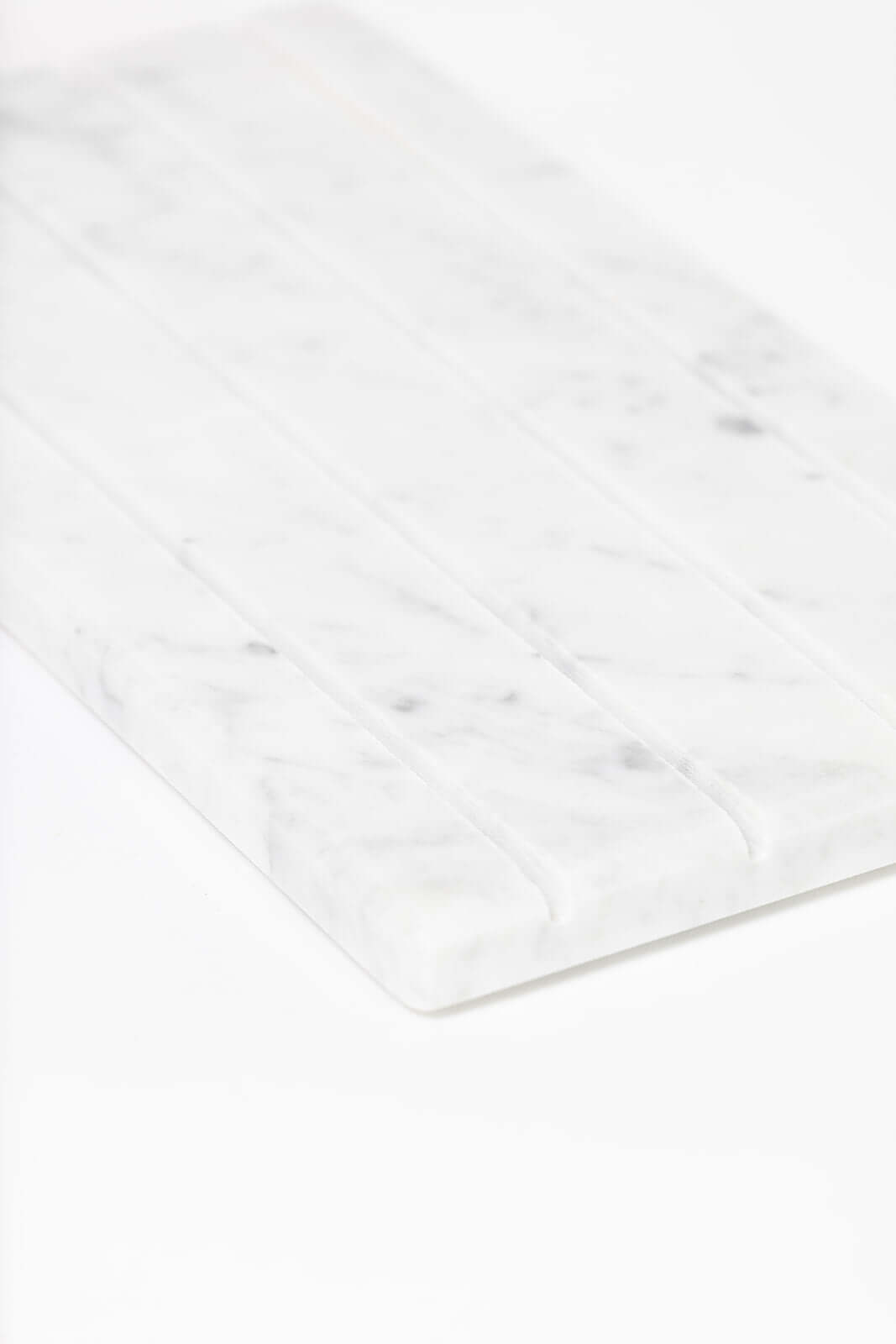 Angled close-up of the white marble jewelry tray highlighting its ridged compartments and marble veining.