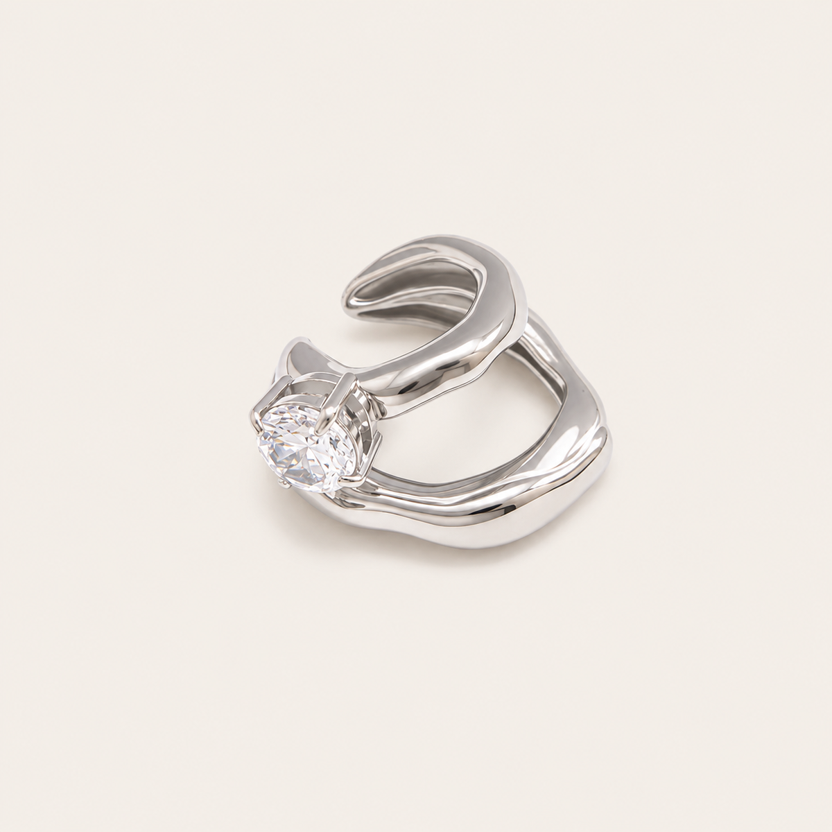The Maya EAR CUFF in silver, a sculptural double-band cuff set with a single round clear gem, shown in a studio close-up.