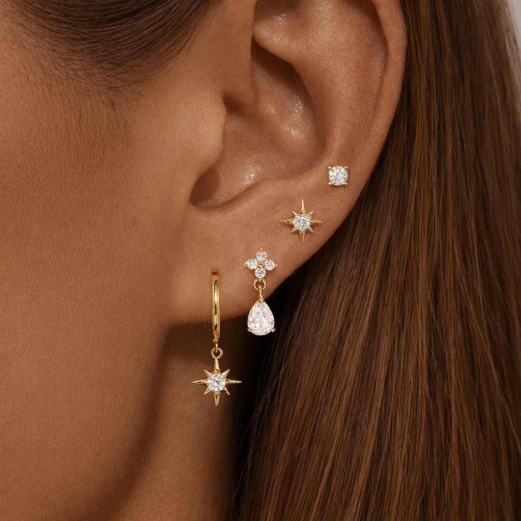 Mila Set worn stacked along the ear, layering a solitaire stud, star stud, pear-crystal drop, and star-charm hoop.