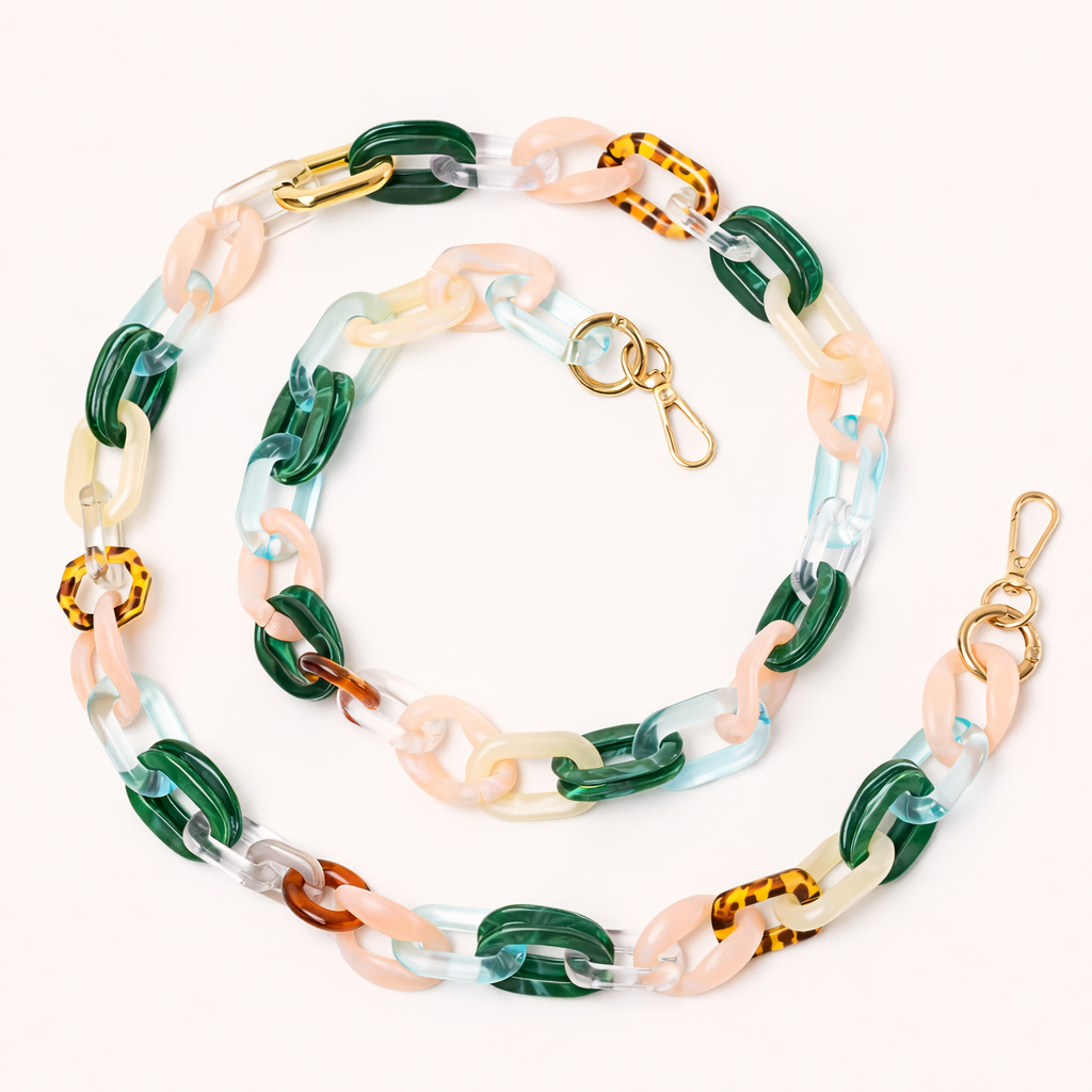 A coiled acrylic link phone chain in green, pink, clear, and tortoiseshell tones with a gold clasp, shown on a cream background.