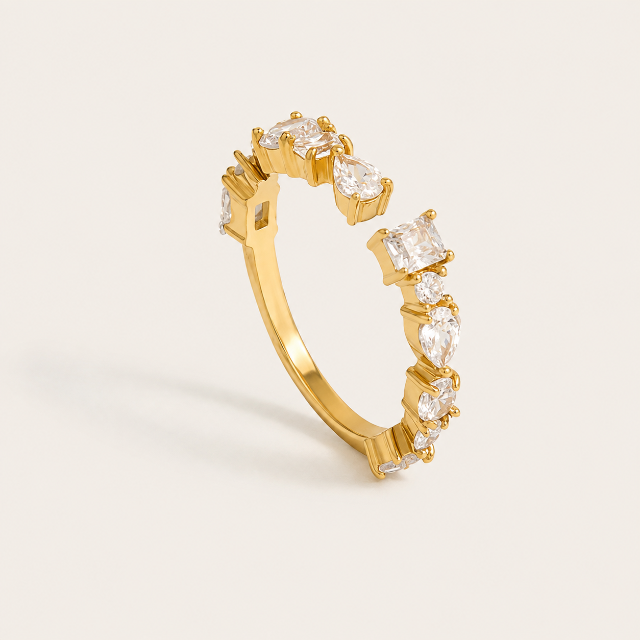 Gold open ring set with a cluster of pear, marquise and princess-cut zirconia stones on a cream backdrop — Folie à Trois Pretty Thing RING.