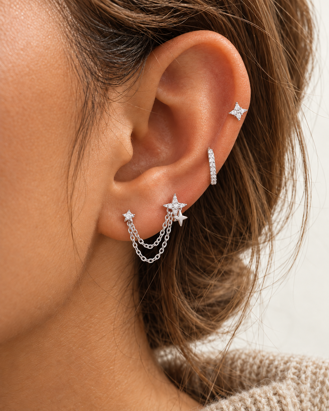 Ear styled with the silver Romy SET: a chain-linked double star stud, a pavé huggie hoop and a four-point star stud up high.