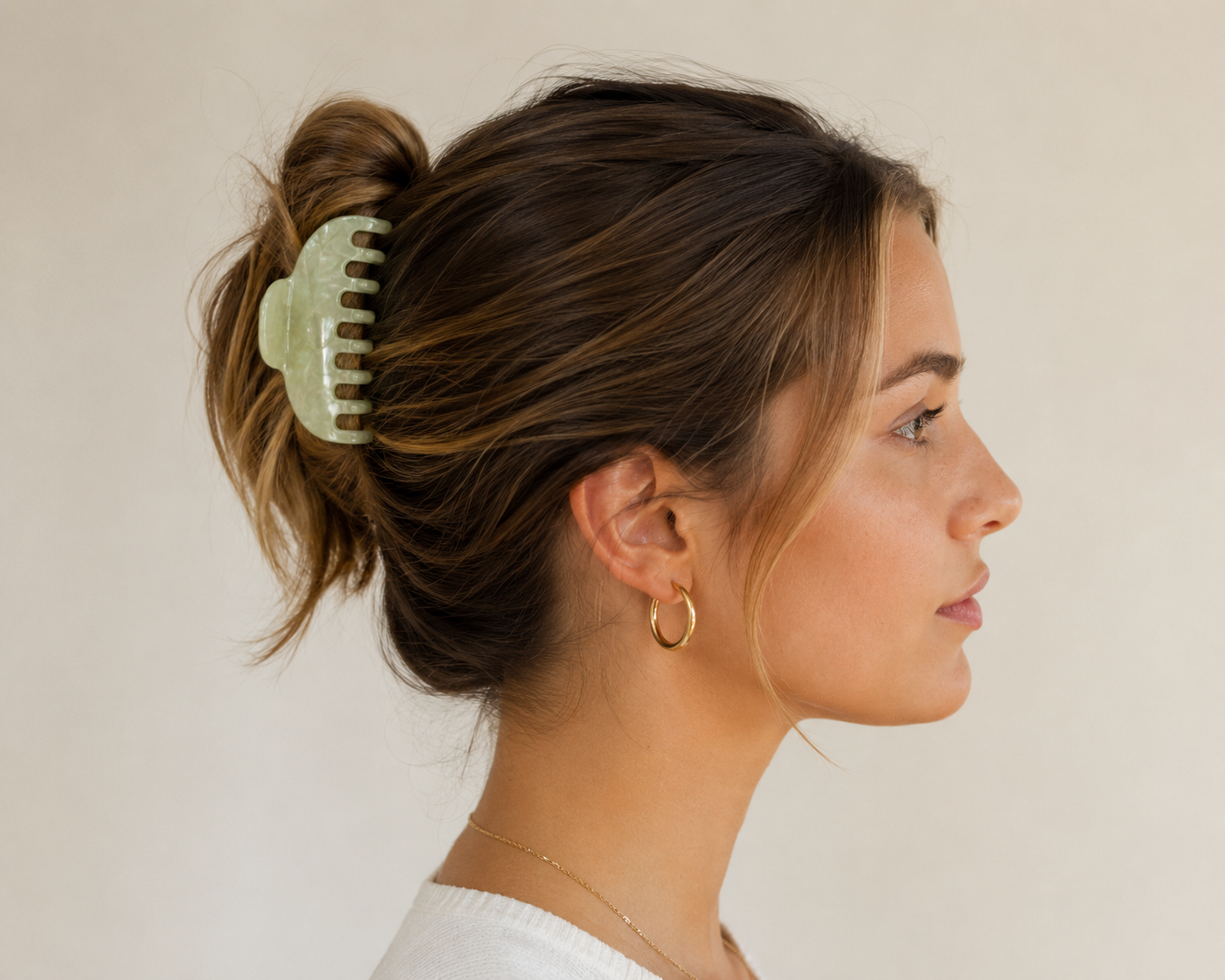 Ruth HAIR CLIP in mint green, worn holding a messy bun, model shown in profile with gold hoop earring.