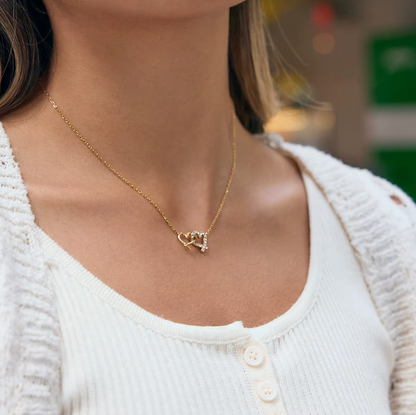 Gold-plated necklace with a delicate chain and interlocking heart-shaped pendant embellished with clear crystals