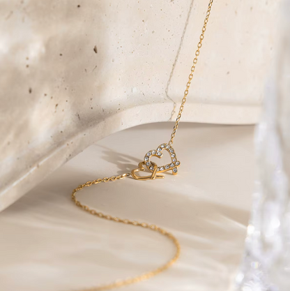Gold-plated necklace with a delicate chain and interlocking heart-shaped pendant embellished with clear crystals