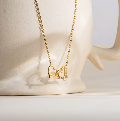 Gold-plated necklace with a delicate chain and interlocking heart-shaped pendant embellished with clear crystals