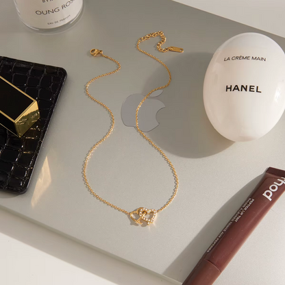 Gold-plated necklace with a delicate chain and interlocking heart-shaped pendant embellished with clear crystals
