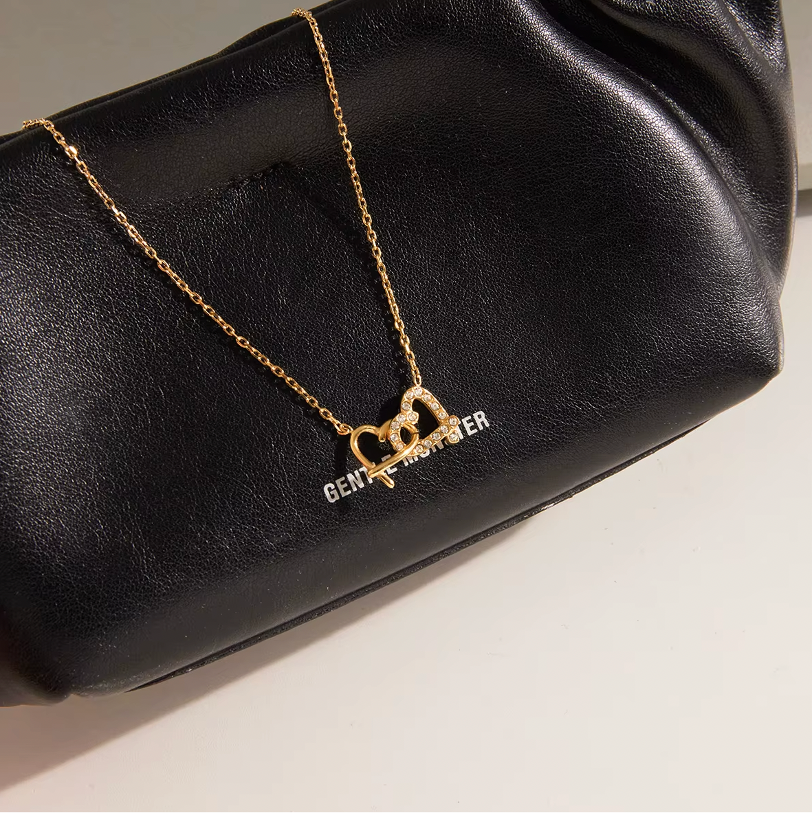 Gold-plated necklace with a delicate chain and interlocking heart-shaped pendant embellished with clear crystals