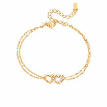 Gold-plated double-chain bracelet with two intertwined heart charms, one polished and one set with clear crystal stones
