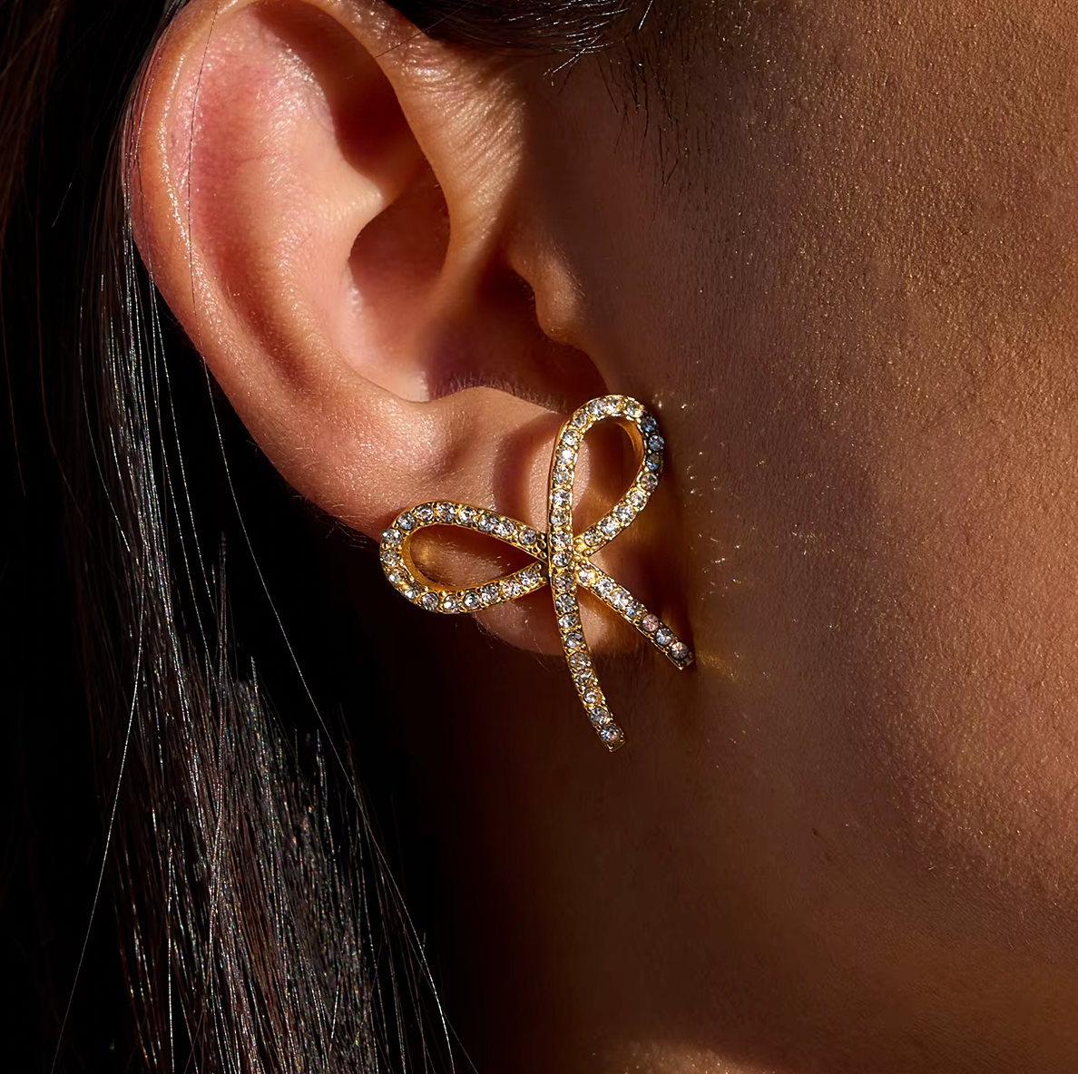 Gold-plated bow-shaped stud earrings embellished with clear crystal stones