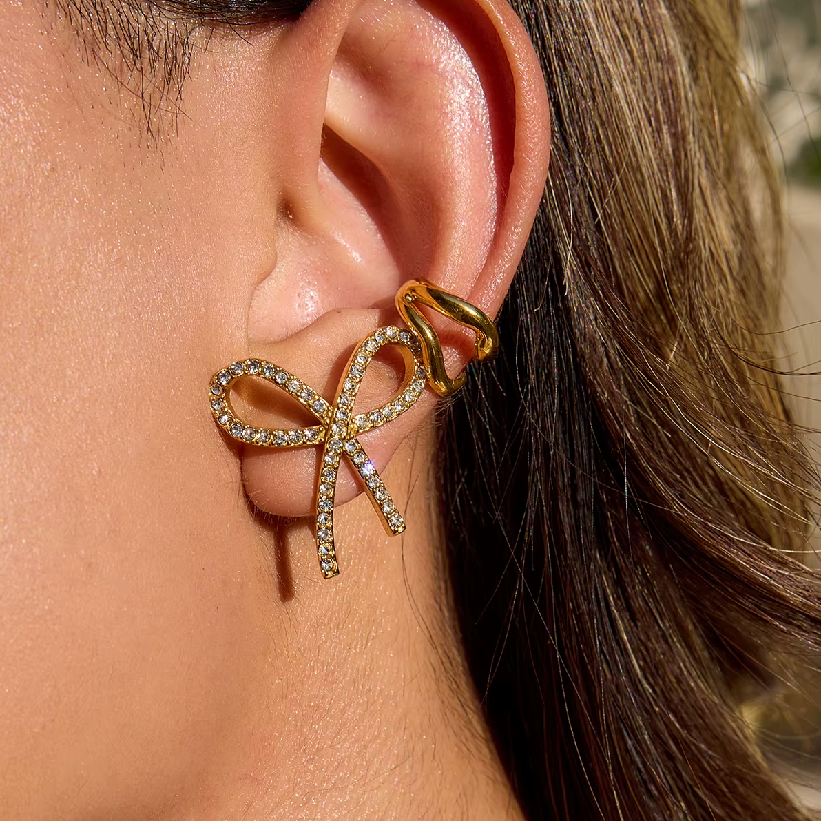 Gold-plated bow-shaped stud earrings embellished with clear crystal stones