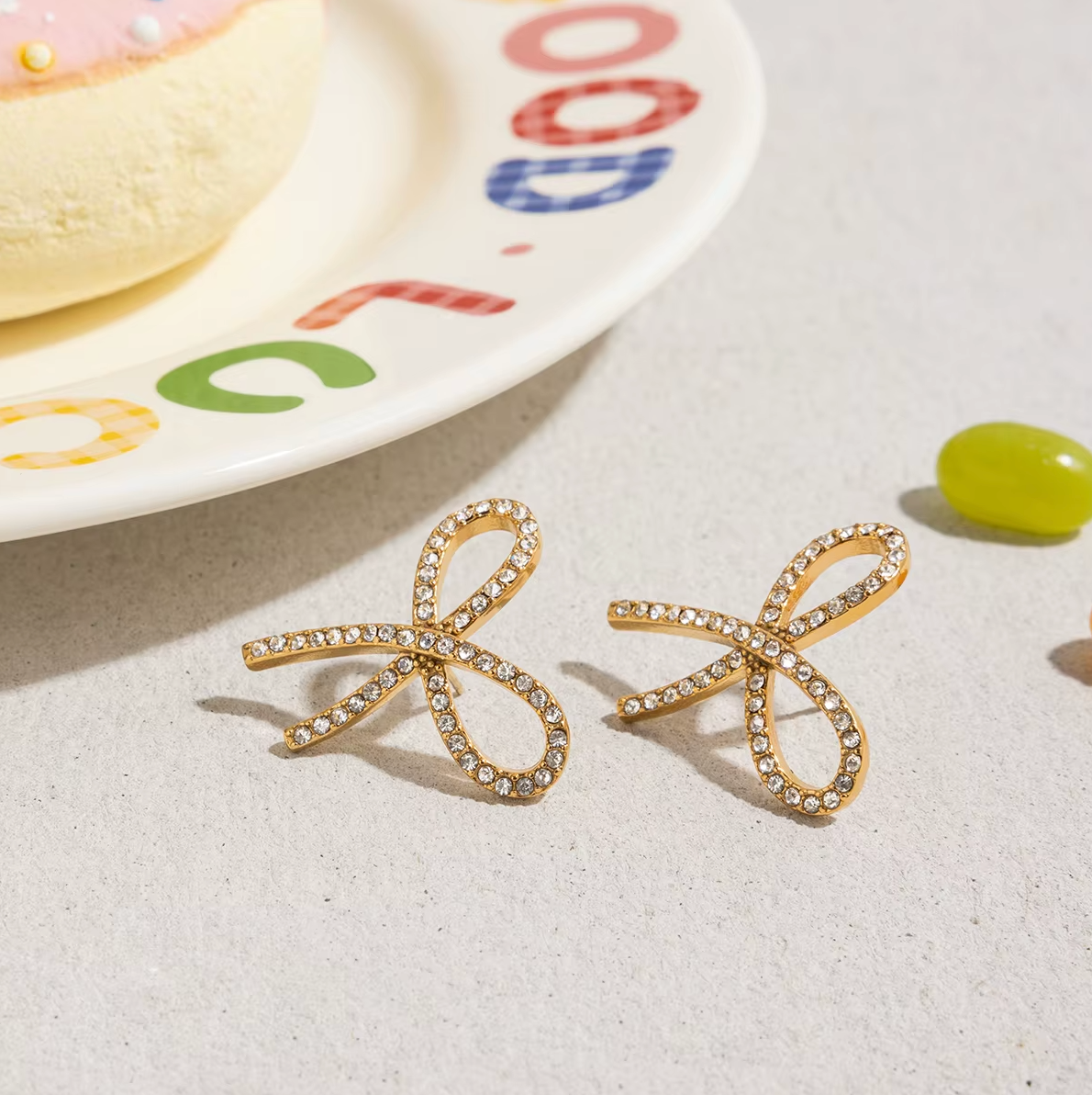 Gold-plated bow-shaped stud earrings embellished with clear crystal stones