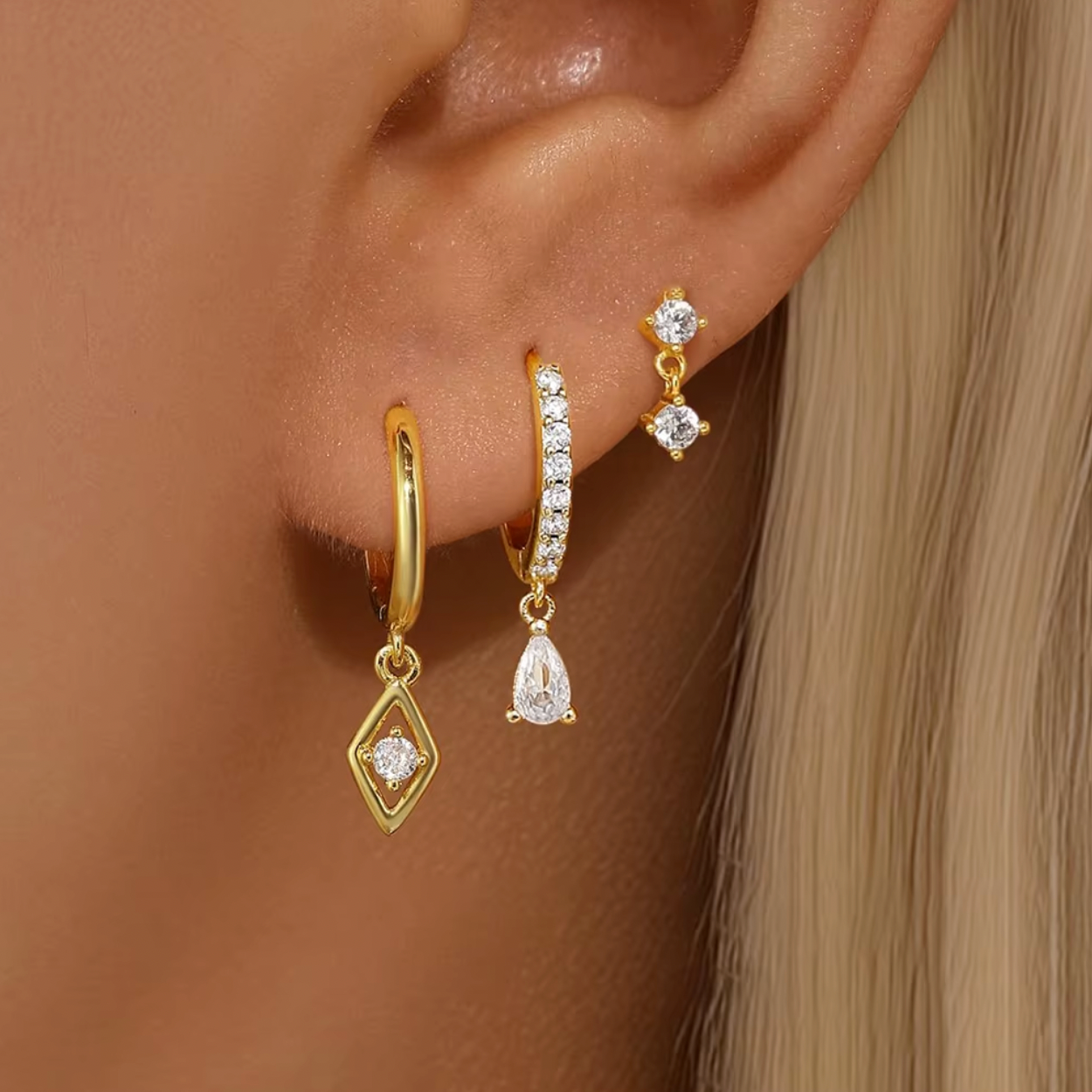 Two matching earring sets displayed on a white background, featuring gold and silver stud and huggie earrings with clear crystal stones and delicate drop charms, arranged vertically.