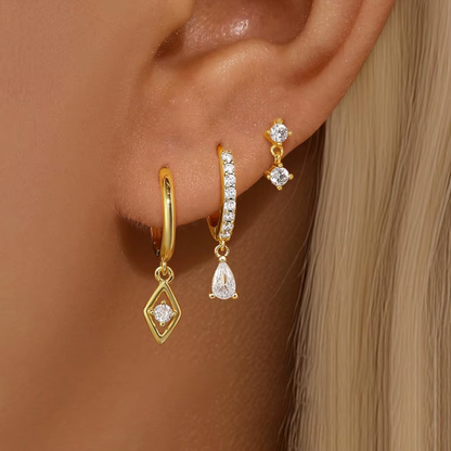 Two matching earring sets displayed on a white background, featuring gold and silver stud and huggie earrings with clear crystal stones and delicate drop charms, arranged vertically.