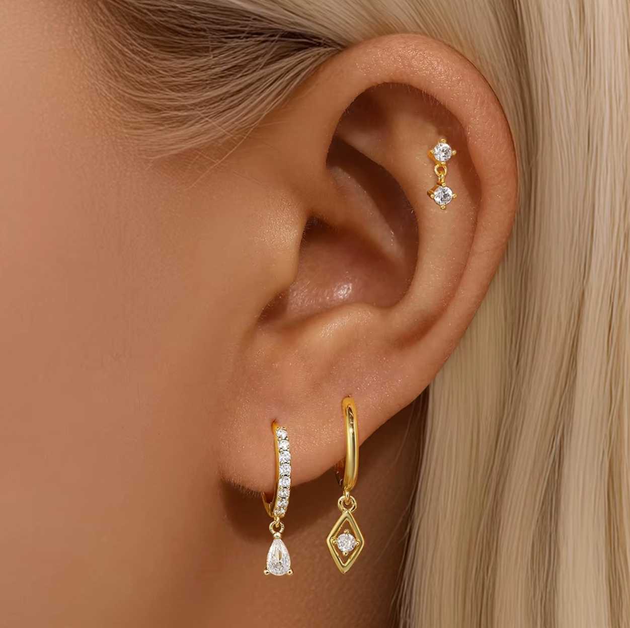 Two matching earring sets displayed on a white background, featuring gold and silver stud and huggie earrings with clear crystal stones and delicate drop charms, arranged vertically.