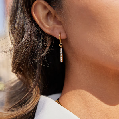 Gold-plated huggie earrings with slim vertical bar pendants set with clear crystal stones