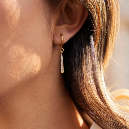 Gold-plated huggie earrings with slim vertical bar pendants set with clear crystal stones