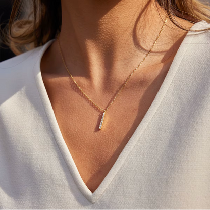 Gold-plated necklace with a fine chain and a slim vertical bar pendant set with clear crystal stones