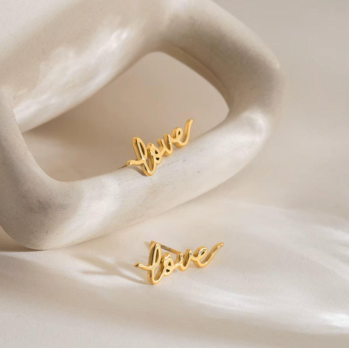 Pair of gold-plated stud earrings spelling “love” in cursive script