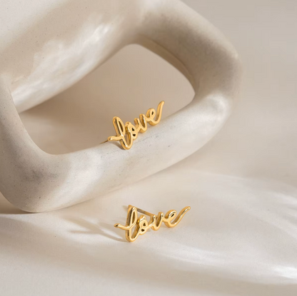 Pair of gold-plated stud earrings spelling “love” in cursive script