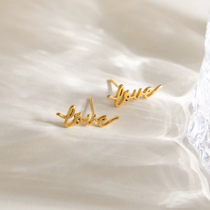 Pair of gold-plated stud earrings spelling “love” in cursive script