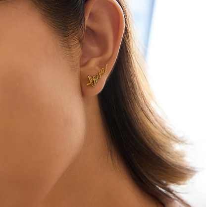 Pair of gold-plated stud earrings spelling “love” in cursive script