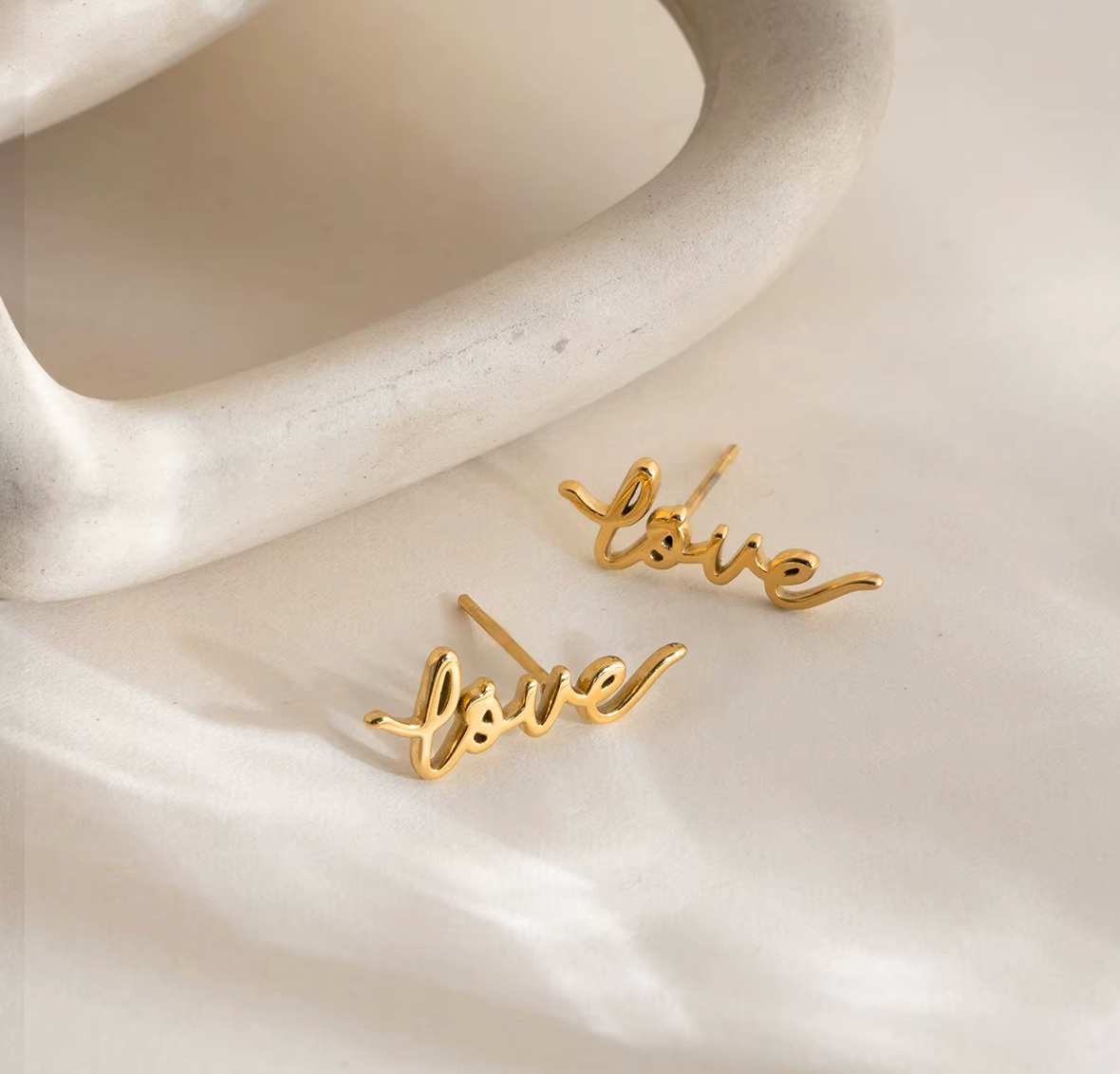 Pair of gold-plated stud earrings spelling “love” in cursive script