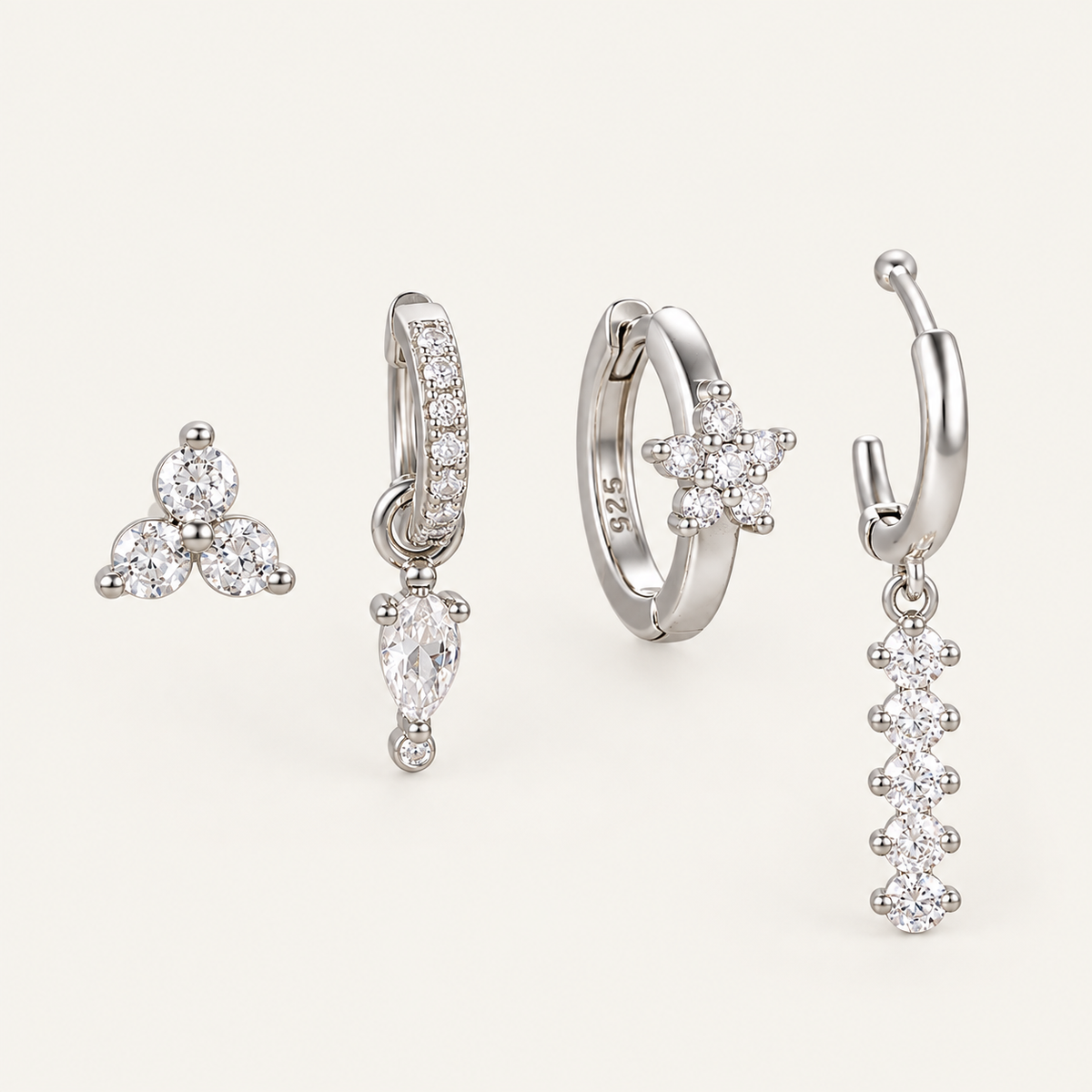 The Folie à Trois Adele SET in silver: a trio stud, a pavé huggie with crystal drop, a flower hoop and a beaded dangle hoop.