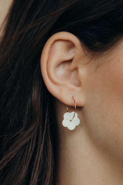 Worn along the ear, After Glow Earrings drop their white flower bead below a delicate gold wire hoop.
