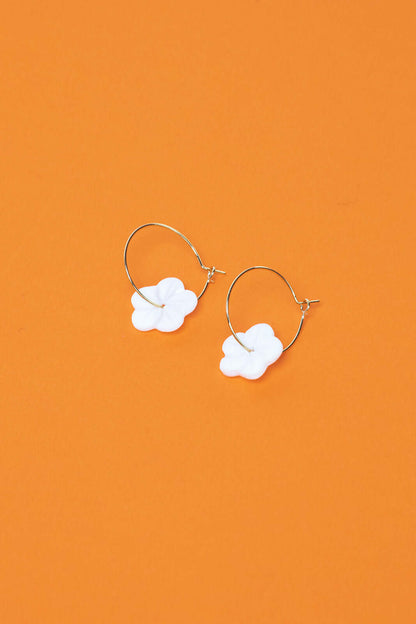 Against a bold orange backdrop, After Glow Earrings show off their white flower bead and slim gold hoop.