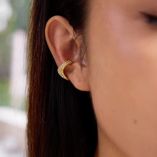 Afterparty Ear Cuff worn on the upper ear cartilage, a wide gold band fully paved with crystals wrapping around the cartilage curve.
