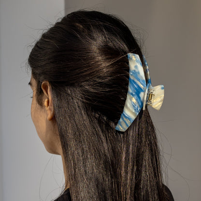 Alba HAIR CLIP in a blue and white striped pattern, worn half-up on dark hair, side view.