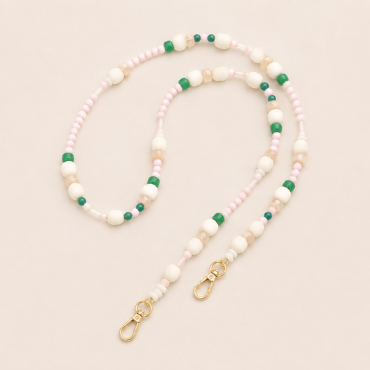 Folie à Trois Alder long wholesale phone chain in pink, cream, sand and green seed and round beads with gold lobster clasps, coiled on a cream background.