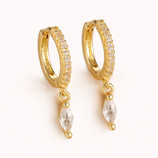 Anette Earrings in gold with clear crystals, a pave huggie hoop dropping a single marquise-cut crystal charm.
