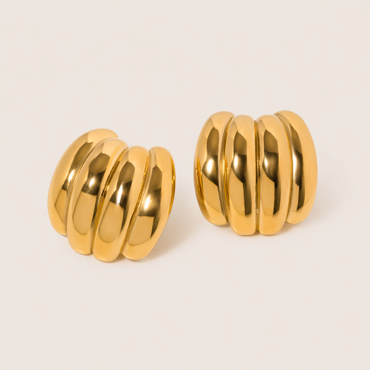 The Ari EARRINGS are chunky gold hoop earrings with a ribbed, fluted texture for a bold, sculptural finish.