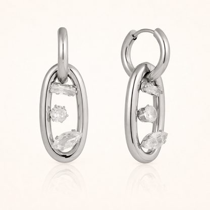 The Astral EARRINGS are shown in polished silver, pairing an open hoop with a crystal-set oval link charm.