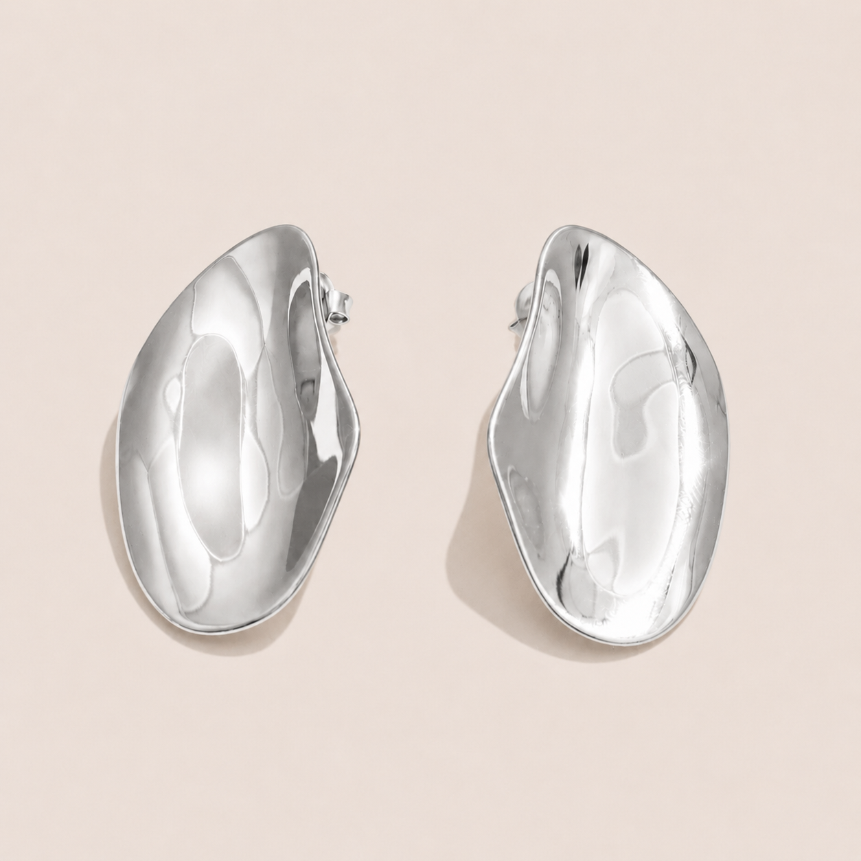 Silver sculptural asymmetric dome stud earrings with a hammered, wavy organic shape on a cream backdrop — Folie à Trois Axis EARRINGS