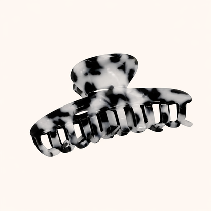 Black and white dalmatian-print acetate claw clip from the Baby Love HAIR CLIP collection, shown on a cream studio background.