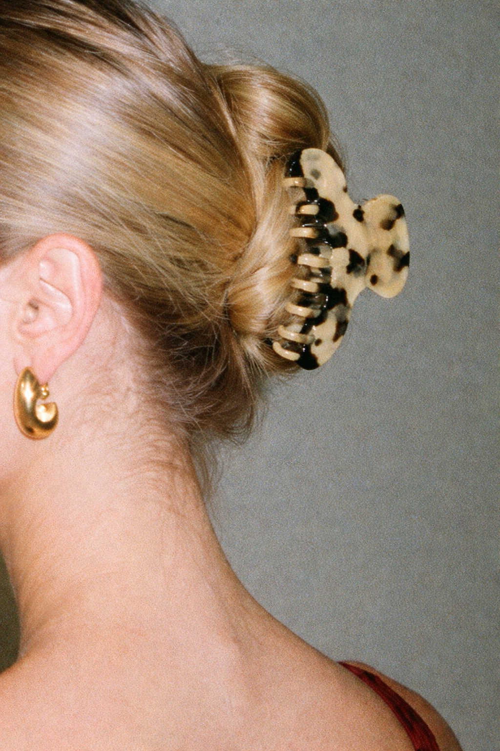 Baby Love HAIR CLIP's cream dalmatian-spotted claw clip worn in a low bun, styled with gold hoop earrings.