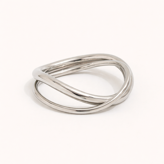 Silver ring made of three interwoven wavy bands, shown at an angle on a cream backdrop — Belance RING.