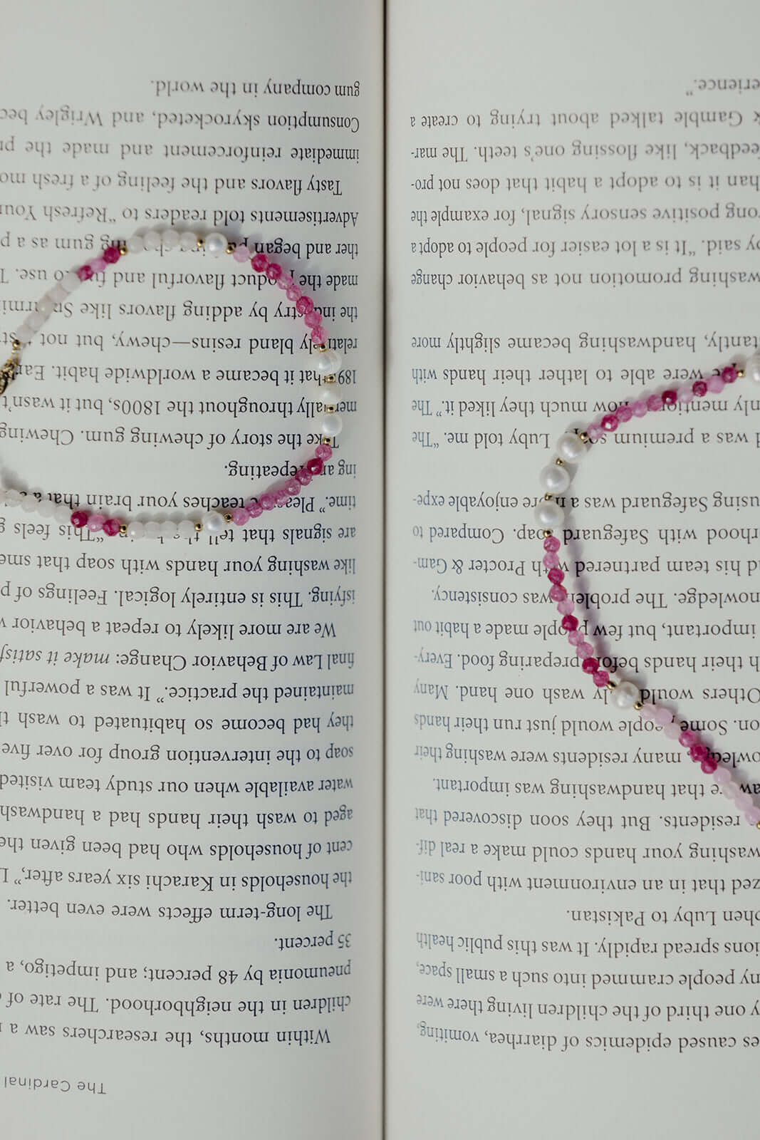 Bianca BRACELET matching pink and white beaded necklace draped across an open book, close-up styled shot.