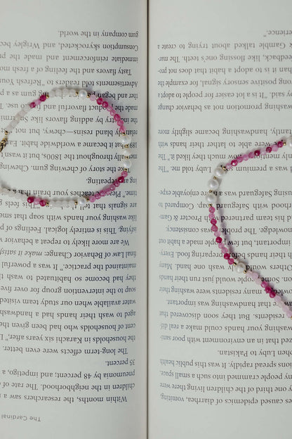 Bianca BRACELET matching pink and white beaded necklace draped across an open book, close-up styled shot.