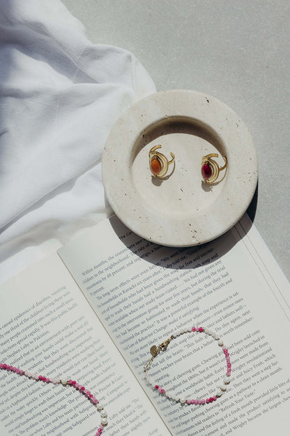 Bianca BRACELET beaded necklace styled on a ceramic dish with gold rings, resting on an open book.