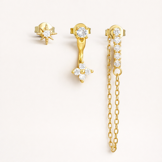 Bianca Set of three gold pieces: a star stud, a flower drop stud, and a crystal bar stud with a delicate draped chain.